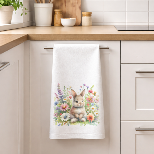 Kitchen towel with a bunny and flowers design hanging on a kitchen rack.