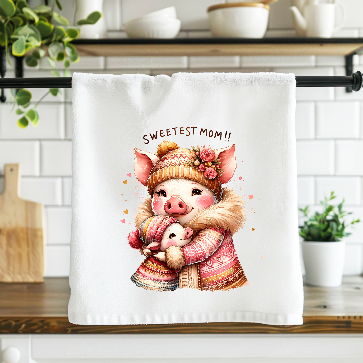 Kitchen towel with a cartoon pig design hanging on a rack in a kitchen.