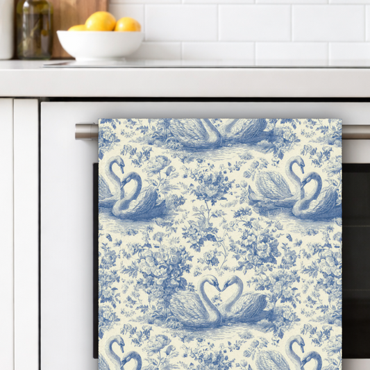 Decorative towel with swan pattern hanging on a kitchen rack.