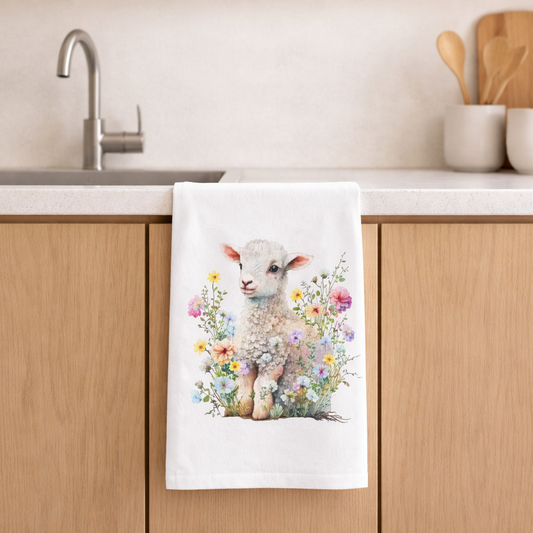 Kitchen towel with a lamb design hanging on a wooden cabinet.