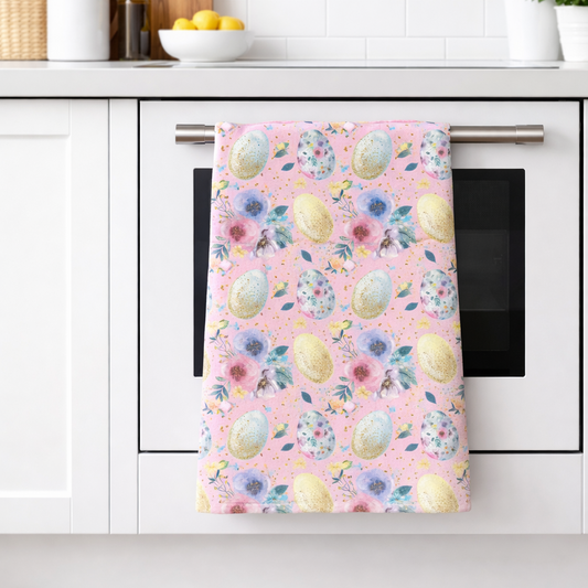 Kitchen towel with floral and Easter egg design hanging on a kitchen cabinet.