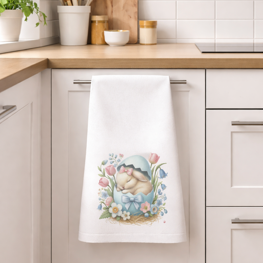 Decorative towel with a baby and flower design hanging on a kitchen cabinet.