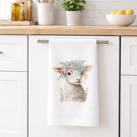 Kitchen towel with a lamb design hanging on a kitchen cabinet.