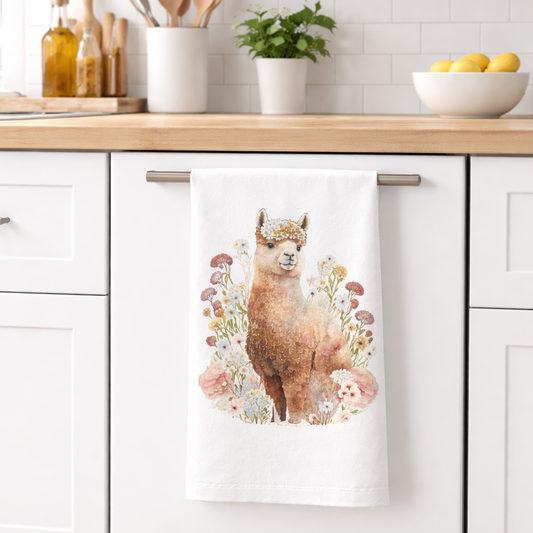 Kitchen towel with an alpaca design hanging on a kitchen cabinet.