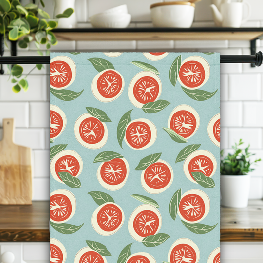 Kitchen towel with tomato pattern hanging on a rack in a kitchen.